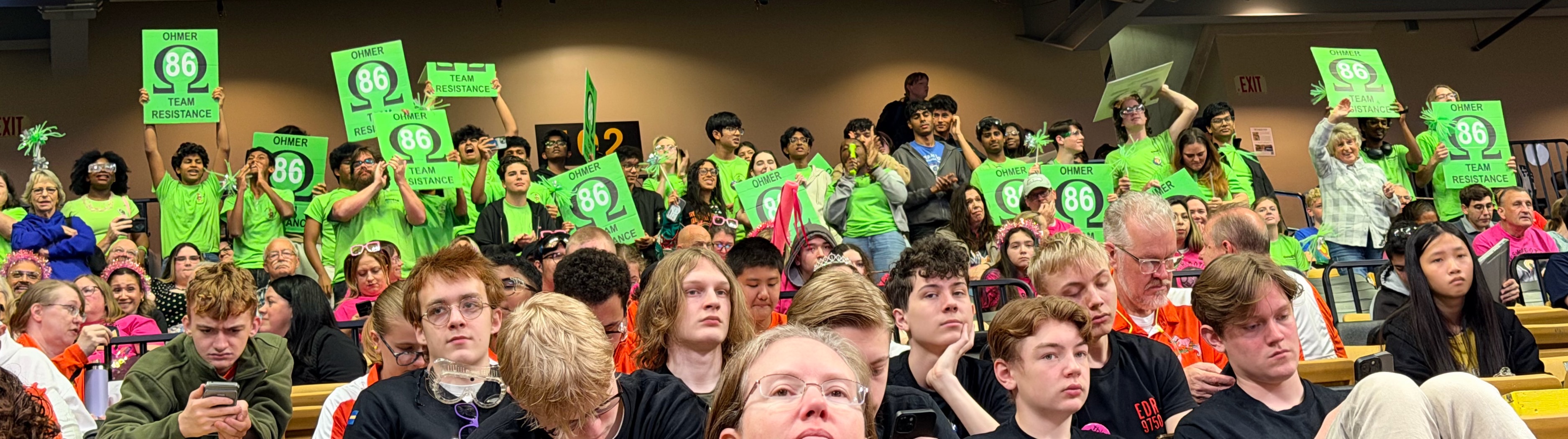 A wide view of the stands with dozens of supporters holding green OHMER 86 signs