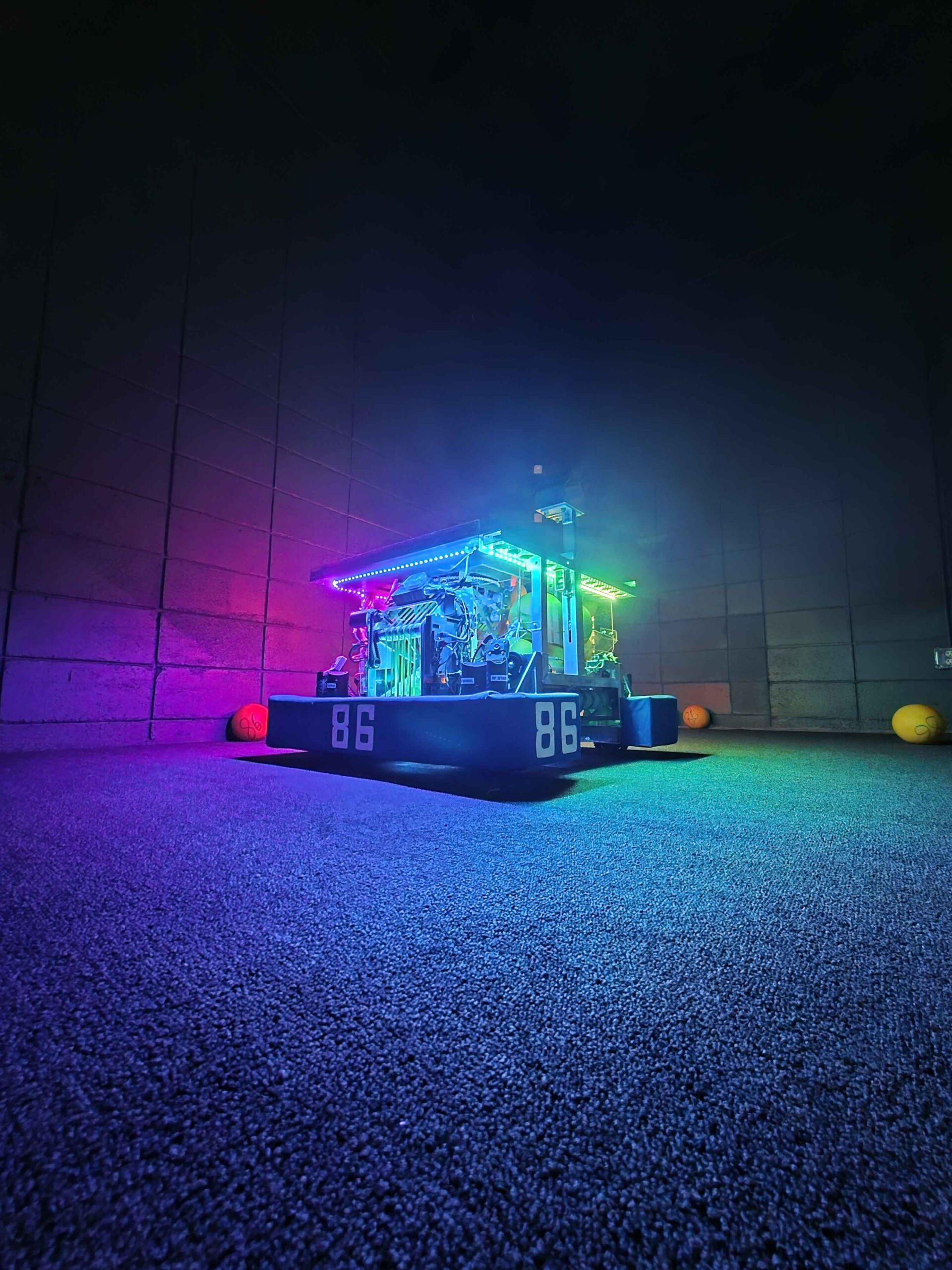 Team 86's robot lit by RGB strips in a darkened shop, its 86 bumpers facing the camera